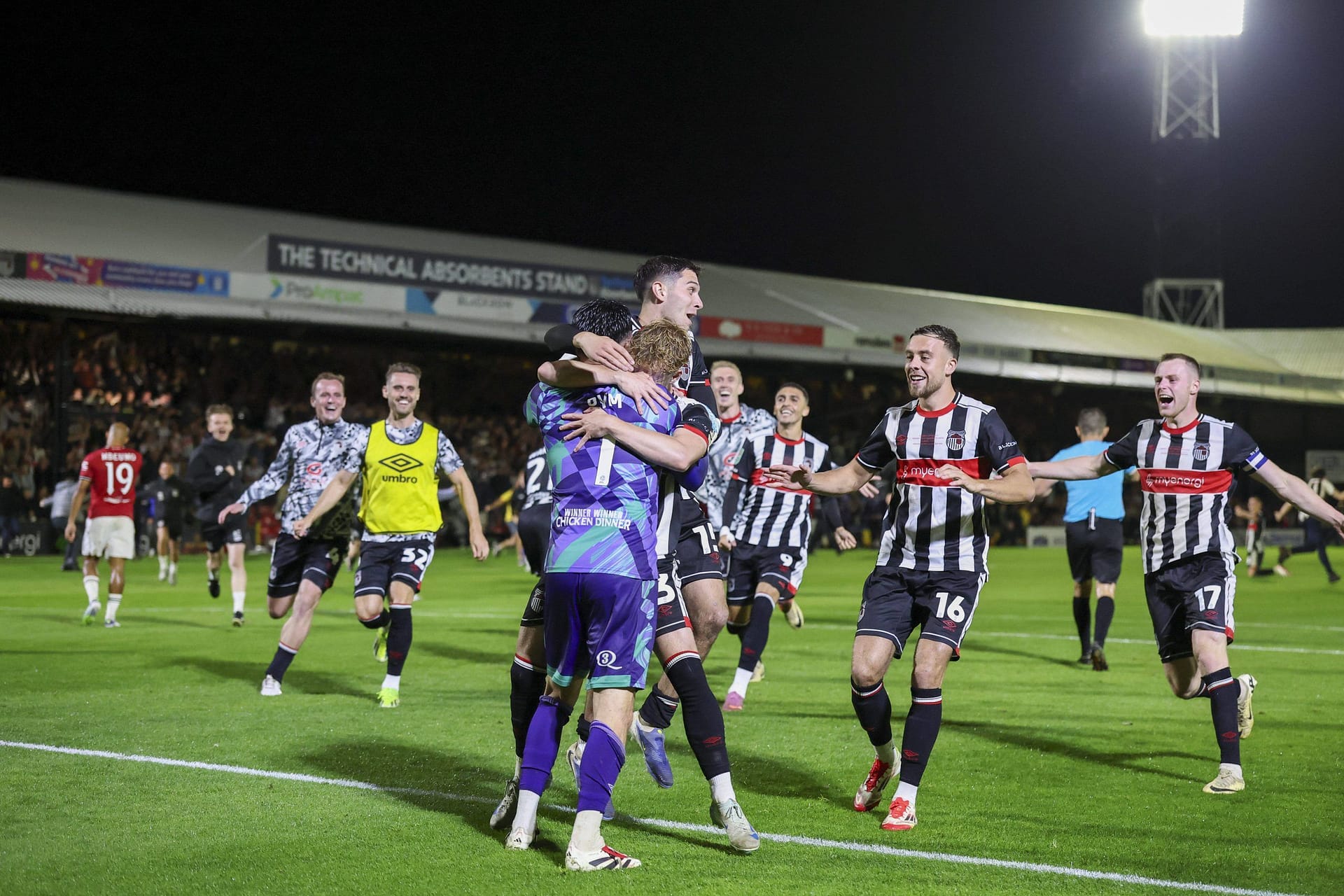Grimsby Town players celebrate penalty shootout victory, including goalkeeper Christy Pym and defender Reece Staunton